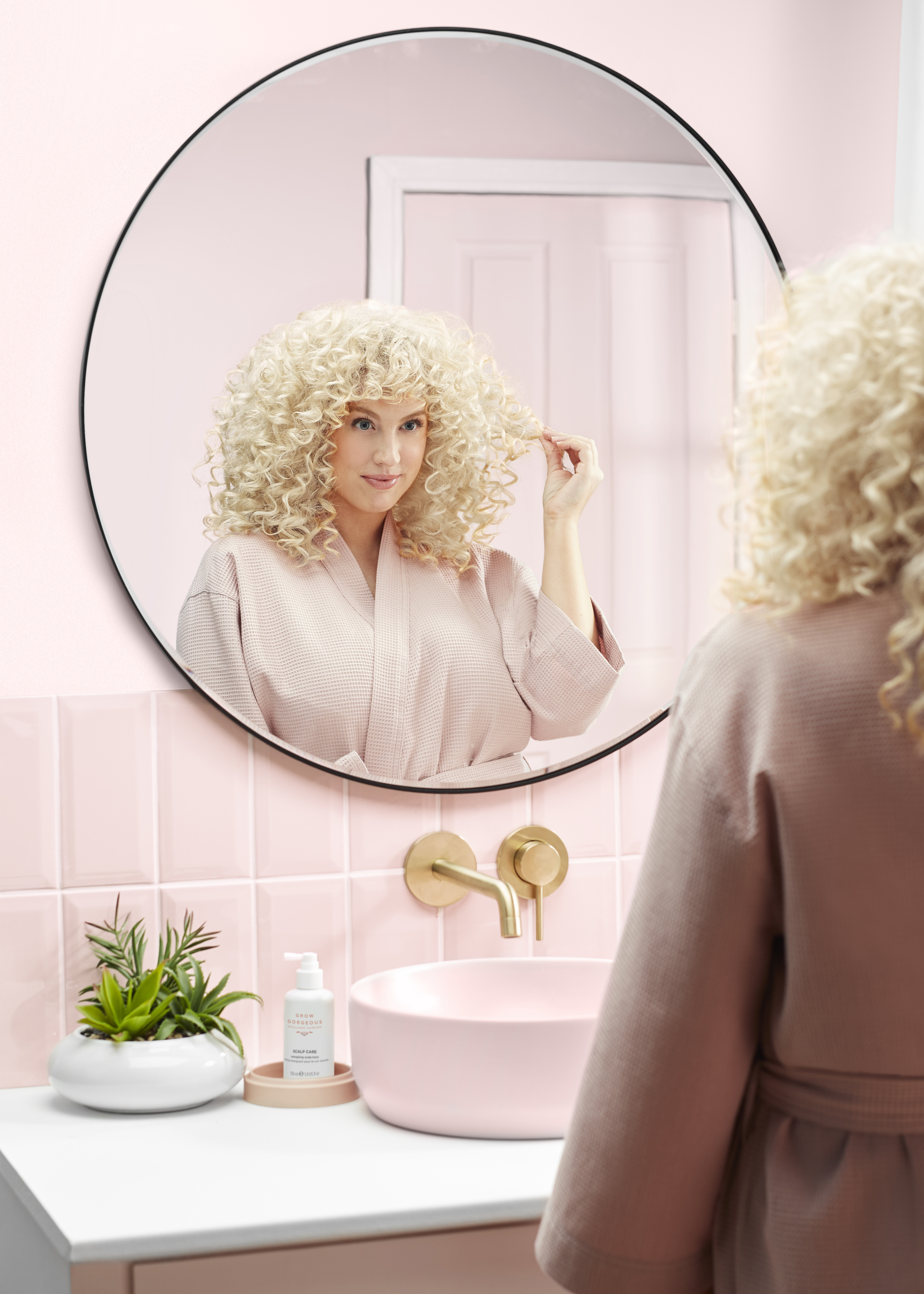 Woman admires her hair in bathroom mirror